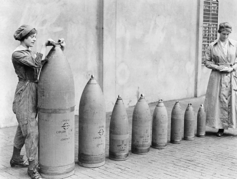 Two women munitions workers stand beside examples of the shells produced at Chilwell, Nottinghamshire, UK