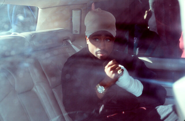 Tupac Shakur sitting in the back of a car