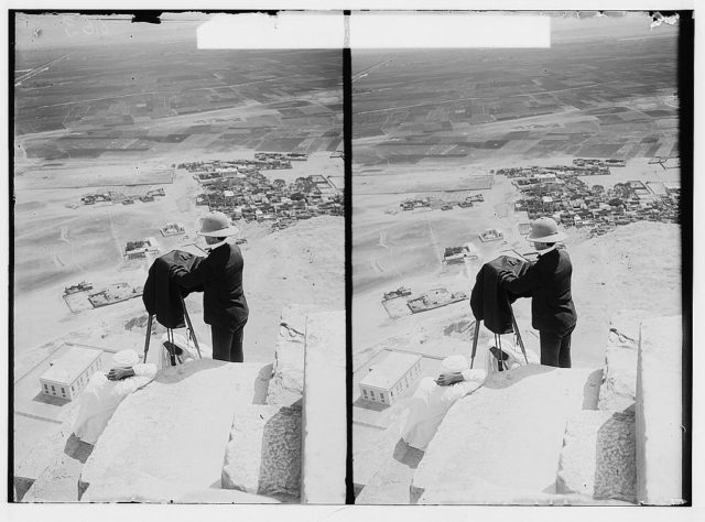 Photograph shows American Colony Photo Department photographer Lewis Larsson with a camera, looking down from near the top of the Great Pyramid, Giza, Egypt. Photo Credit 