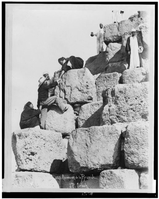 Tourist being helped up the great pyramid by Egyptian men Photo Credit 
