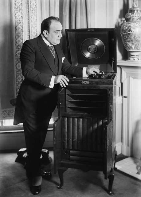 Famous opera singer, Enrico Caruso, with a customized Victrola given to him as a wedding gift by the Victor Company in 1918.