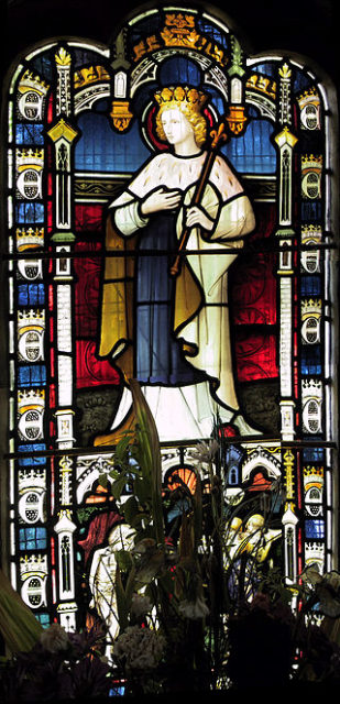 A stained glass window depicting St Edmund, visible inside the church  Photo Credit
