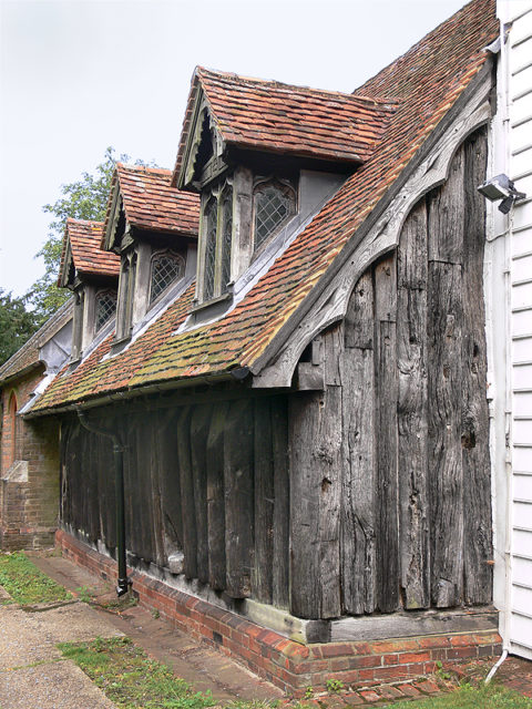 The north wall and part of the west wall of the nave; the notch, low down on the 7th trunk along from the corner, may either be a “leper’s squint,” or a Saxon window