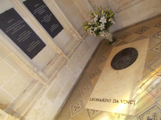 It is a simple granite grave with a bronze medallion on the top   Photo Credit