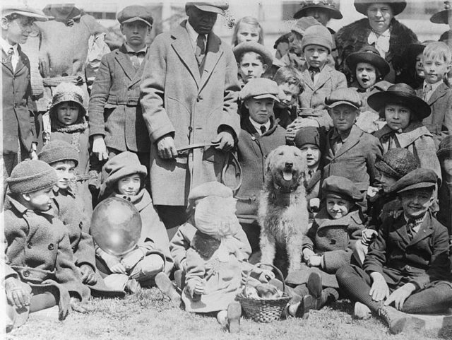 Group of children and adults sitting and standing around President Warren G. Harding’s dog, Laddie Boy, at the 1923 White House Easter egg roll