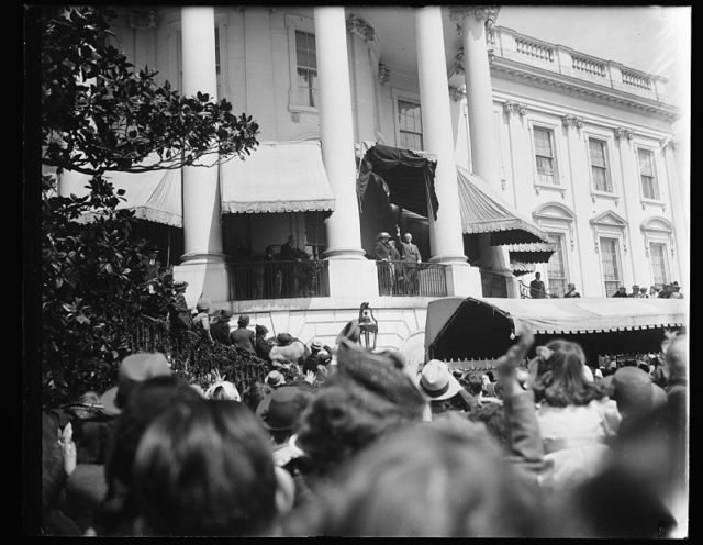 President and Mrs. Roosevelt wave a greeting to the thousands of youngsters who gathered on the White House lawn to roll their gaily colored Easter eggs. Washington, D.C. April 10, 1939.
