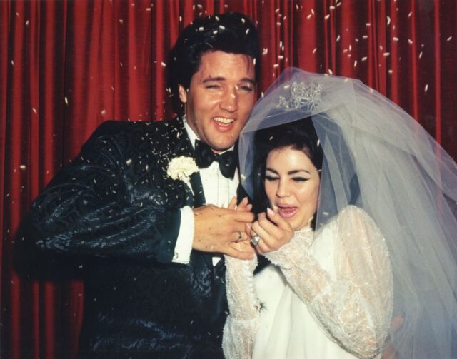 Elvis and Priscilla Presley standing in wedding attire