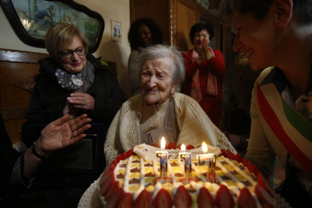 Emma Morrano surrounded by loved ones, a 117 birthday cake in front of her.
