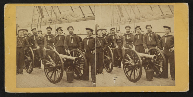 Photograph shows a group portrait of seamen gathered around a mounted gun. The young boy seated on the gun is possibly the powder monkey. LOC