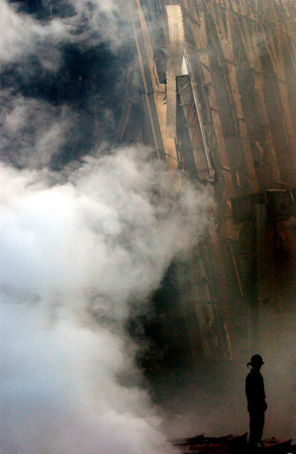 New York, N.Y. (Sept. 14, 2001) — A solitary firefighter stands amidst the rubble and smoke in New York City. Days after the Sept 11 terrorist attack, fires still burn at the site of the World Trade Center
