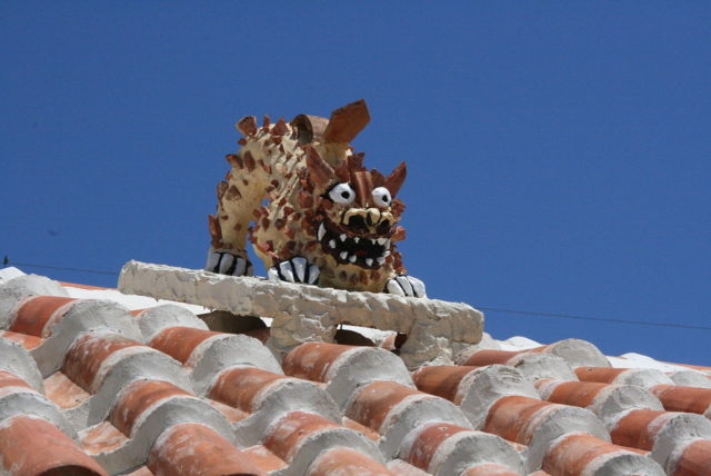 A gargoyle-like Shisa on a roof  Photo Credit