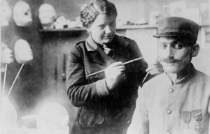 Anna Coleman Ladd working on a prosthetic that's on a soldier's face