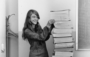 Margaret Hamilton stands next to the navigation software that she and her MIT team produced