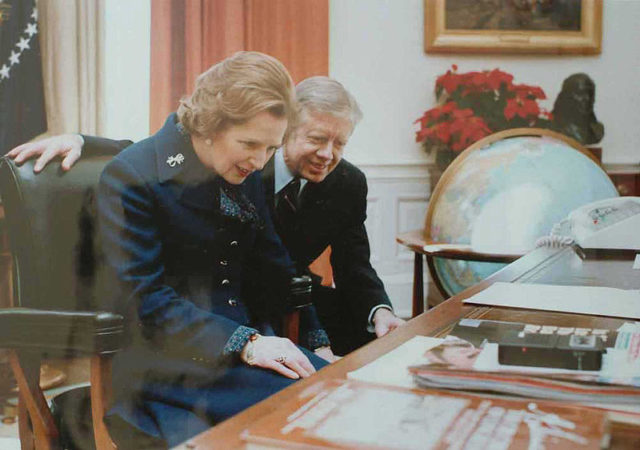 British Prime Minister Margaret Thatcher reads the inscription on the front of the desk in 1979, accompanied by President Jimmy Carter.