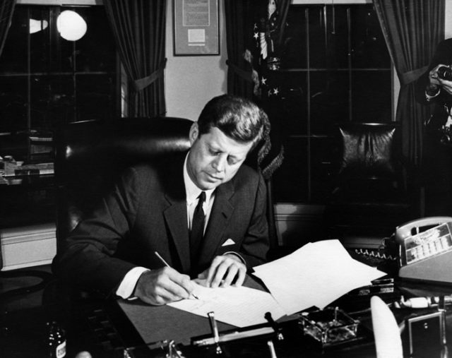 President Kennedy signs Proclamation 3504, authorizing the naval quarantine of Cuba.