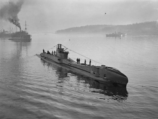 HMS Thunderbolt stationary in harbor after a patrol. Crew members on deck.