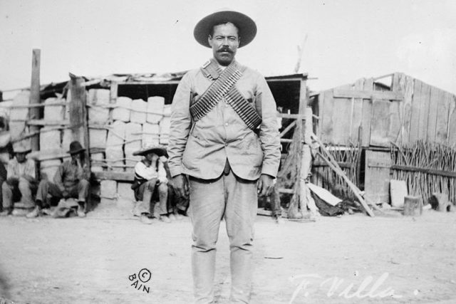 Villa wearing bandoliers in front of an insurgent camp. Undated photo.