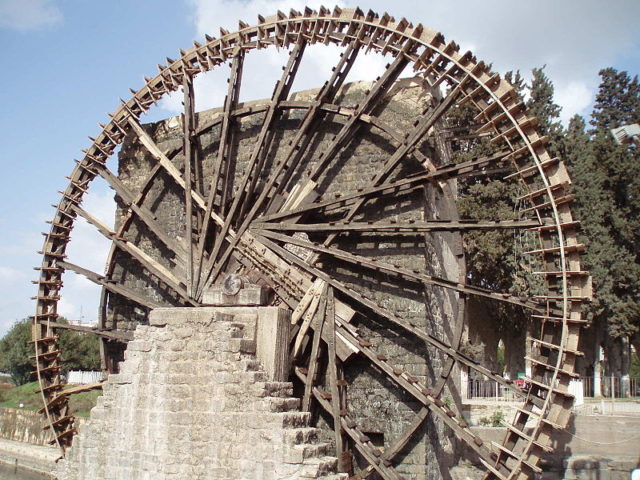 For centuries the Norias of Hama lifted water into small aqueducts to irrigate the fields surrounding the Syrian city. Using the force of gravity to transport water over long distances, the water wheel became a very important symbol of the Islamic influence upon irrigation technology. Author – David Holt – CC BY-SA 3.0.