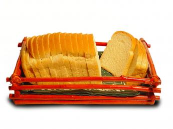 A loaf of white bread sliced to uniform thickness by a bread-slicing machine