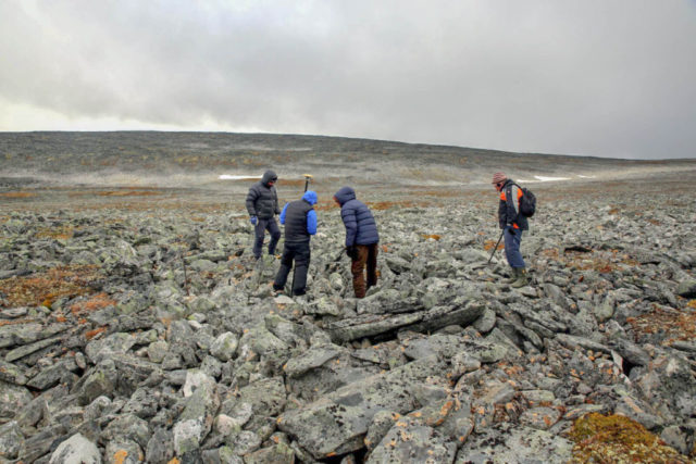 Øystein Rønning Andersen measuring the exact find spot of the sword together with the reindeer hunters. Detectorist Egil Bjørnsgård (right) has started checking for signals in the scree. Photo: Espen Finstad, Secrets of the Ice/Oppland County Council.