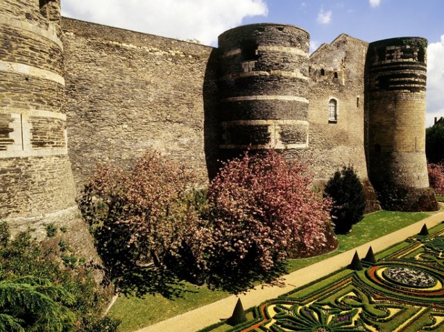 The outer walls and formal gardens of the old medieval chateau at Angers. This is in the Maine-et-Loire department of the Western Loire region of the Loire valley in France.