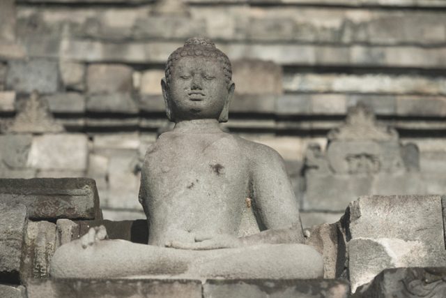 Magelang, Indonesia – April 7, 2015: The walls of Borobudur, a 9th Century Buddhist Temple located in Central Java are lined with so many Buddha sculptures that it one of the largest collections in the world. Lined up the Buddha figures face outwardly from their set positions.
