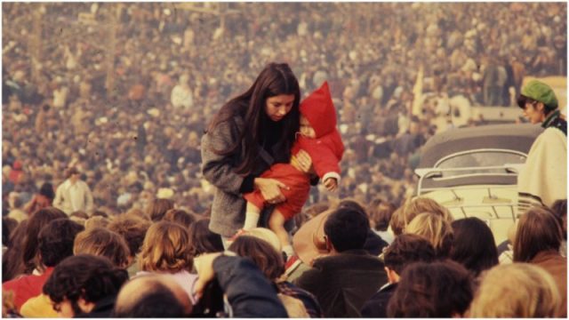 A woman carries a child through the audience at the Altamont Speedway prior to the free concert headlined by the Rolling Stones. Photo by William L. Rukeyser/Getty Images