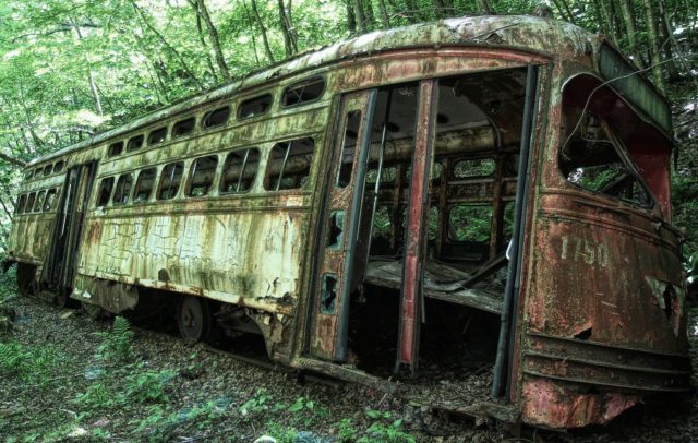 Dozens of trolleys and train cars from PA, MA, KS, in various states of decomposition. Mother Nature has been hard on these once-cherished machines. Author: Forsaken Fotos, CC BY 2.0