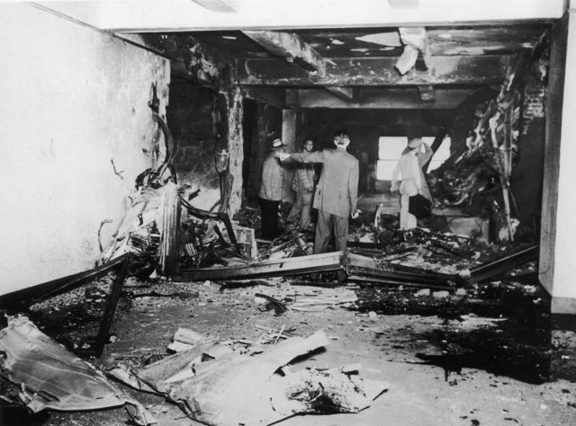 Men standing within a burned corridor