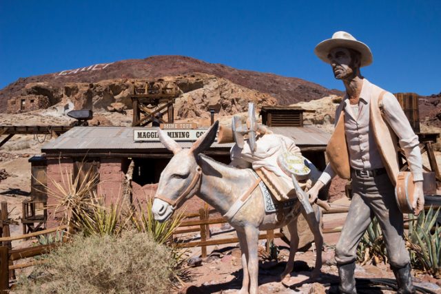 Calico, California, United States – March 14, 2014: A statue of a miner and his donky in Calico, a former silver mining town founded in 1881 and is now a county park featuring campgrounds and Ghost Town tourist attractions including restaurants and shops.