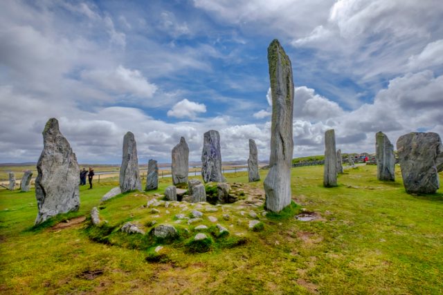 Tourists visiting the Callanish Standing Stones historical site, erected in the late Neolithic era on the west coast of Lewis in the Outer Hebrides – Scotland