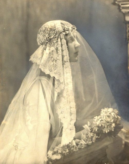 Close-up of actress Rosamund Pinchot in profile, wearing a wedding headdress of heavily embroidered tulle overlaying antique lace, held by orange blossom wreath. (Photo by Edward Steichen/Condé Nast via Getty Images)