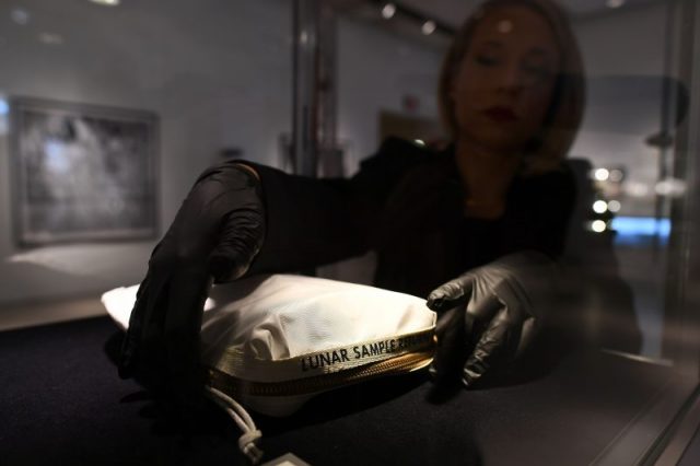 Sothebys Cassandra Hatton adjusts the Apollo 11 Contingency Lunar Sample Return Bag, used by Neil Armstrong on Apollo 11 to bring back the very first pieces of the moon ever collected, during a media preview for Space Exploration auction in New York on July 13, 2017. / (Photo credit JEWEL SAMAD/AFP/Getty Images)
