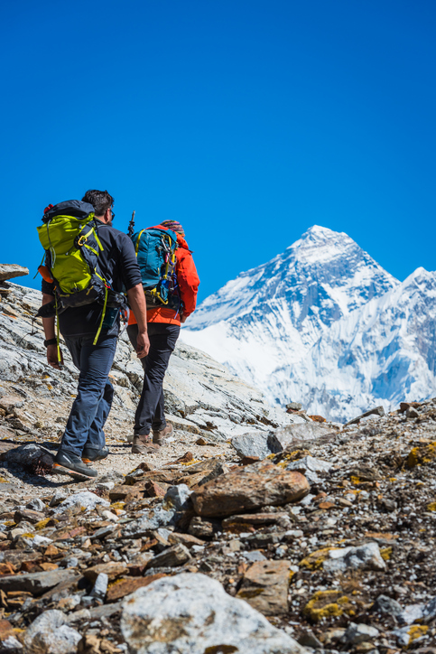 Mountaineers hiking along the rocky trail of the Renjo La below the iconic summit pyramid of Mt. Everest (8841m) deep in the Himalayan mountain wilderness of the Sagarmatha National Park, Nepal.