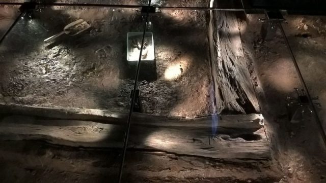 Under a glass floor, the original archaeological dig is reproduced with actual timbers. Photo By Chemical Engineer – CC BY-SA 4.0