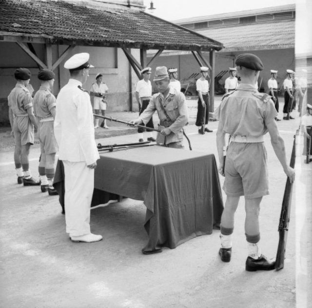 A Japanese naval warrant officer surrenders his sword to Sub Lieutenant Anthony Martin in a ceremony in Saigon.