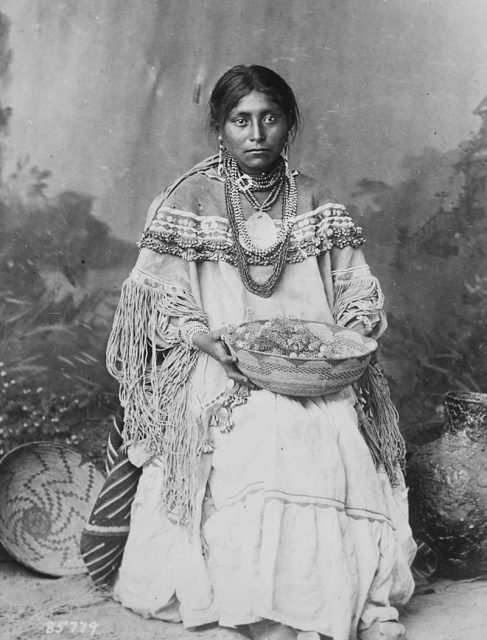Apache bride in a traditional dress, wearing a large statement-piece shell necklace and beaded chocker.