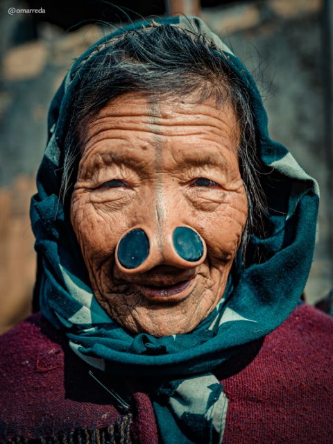 Close up shot of an old lady with her quite prominent nose plugs. Photo by Omar Reda