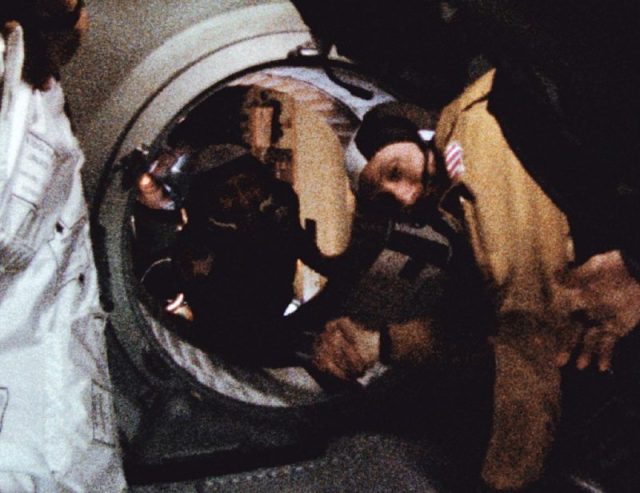 Astronaut Thomas P. Stafford and cosmonaut Aleksei Leonov shake hands in space to ease Cold War tensions.