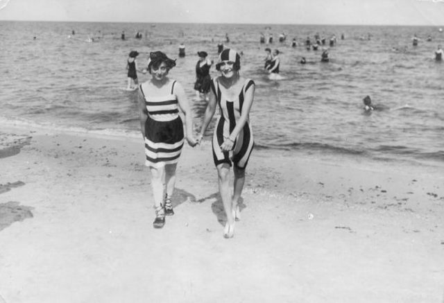 Life at the beach in Heringsdorf, at the Baltic Sea. Two women of the area wearing beautiful striped costumes (1909). Photo by Haeckel, Otto CC-BY-SA 3.0