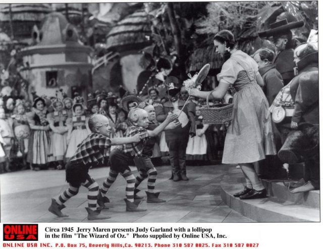 1939: Jerry Maren, playing a Lollipop Guild Member, presents Judy Garland with a lollipop in the film ‘The Wizard of Oz.’ photo: Getty Images