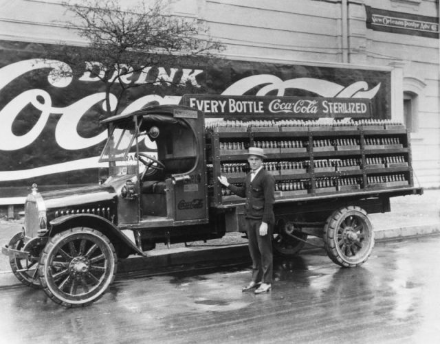 A driver in New Orleans stands in front of his Coca-Cola delivery truck full of cases of the bottled soft drink, 1929.