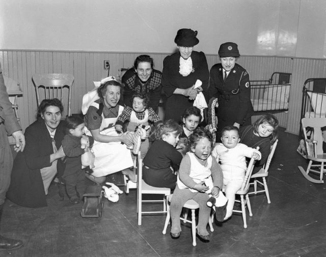Immigrant children with Red Cross port workers, Pier 21, Halifax, Nova Scotia, Canada, 1948.
