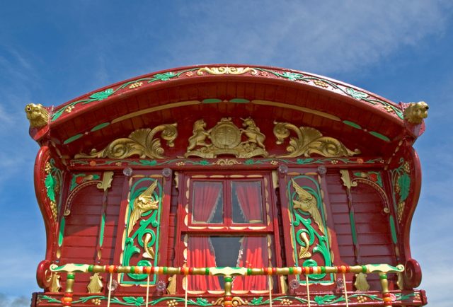 A Romani caravan, decorated with the Royal Coat of Arms of the United Kingdom above the window and two traditional Romanichal Chiriklo (bird of happiness) on the shutters.