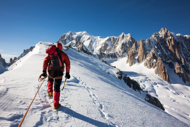 Mountaineer traverses a snowy ridge.