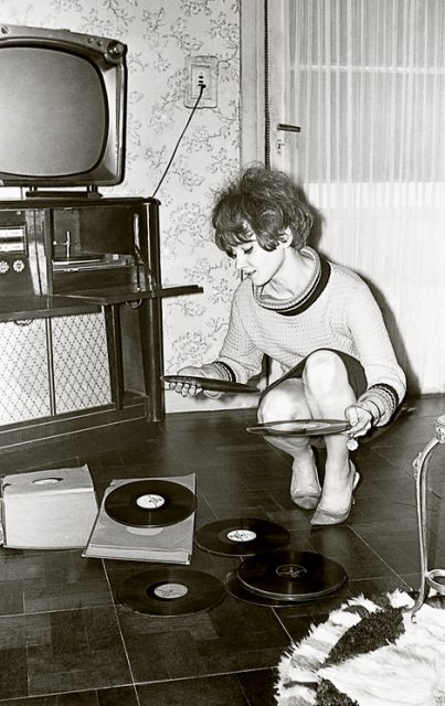 Vintage black and white photo from the sixties of a young woman looking at vinyl records.