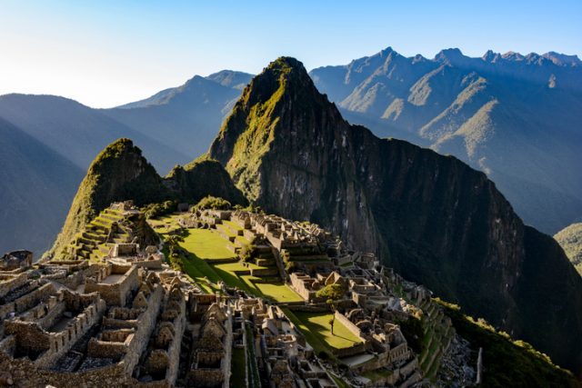 High angle view of the ancient Inca ruins of Machu Picchu as seen from the approach along the Inca trail. Mount Huayna Picchu is in the background.