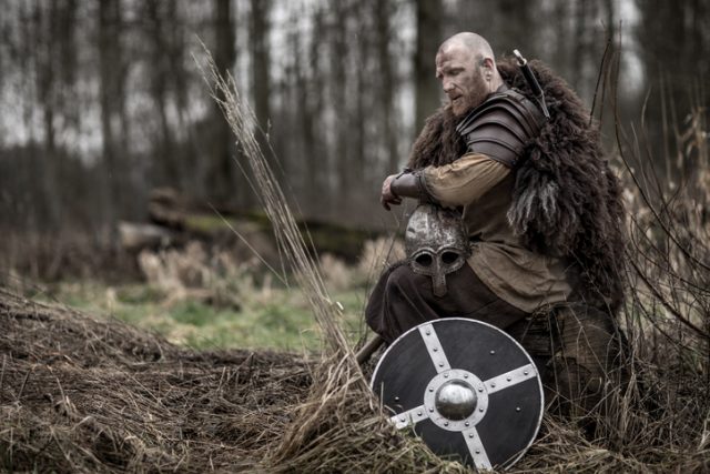 Sword wielding viking warrior alone in a winter forest.