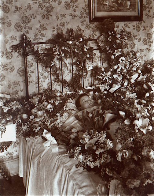 Post-mortem photograph of young child with flowers. 19th Century