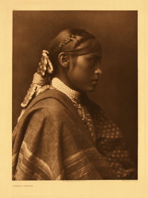 A portrait by photographer Edward S. Curtis showing Sigesh, an unmarried woman. The girl sports a hairstyle and outfit typical for the day, c. 1905.